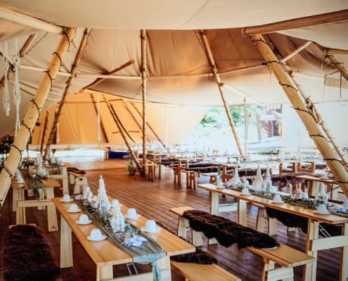 Zwei Stratus 72 Tipis von Tipi-Zauber im Verbund Zwei Stratus 72 Tipis von Tipi-Zauber im Verbund mit Bereich zum verweilen und für Catering und DJ mit Sitzgelegenheiten und Dekorationen.